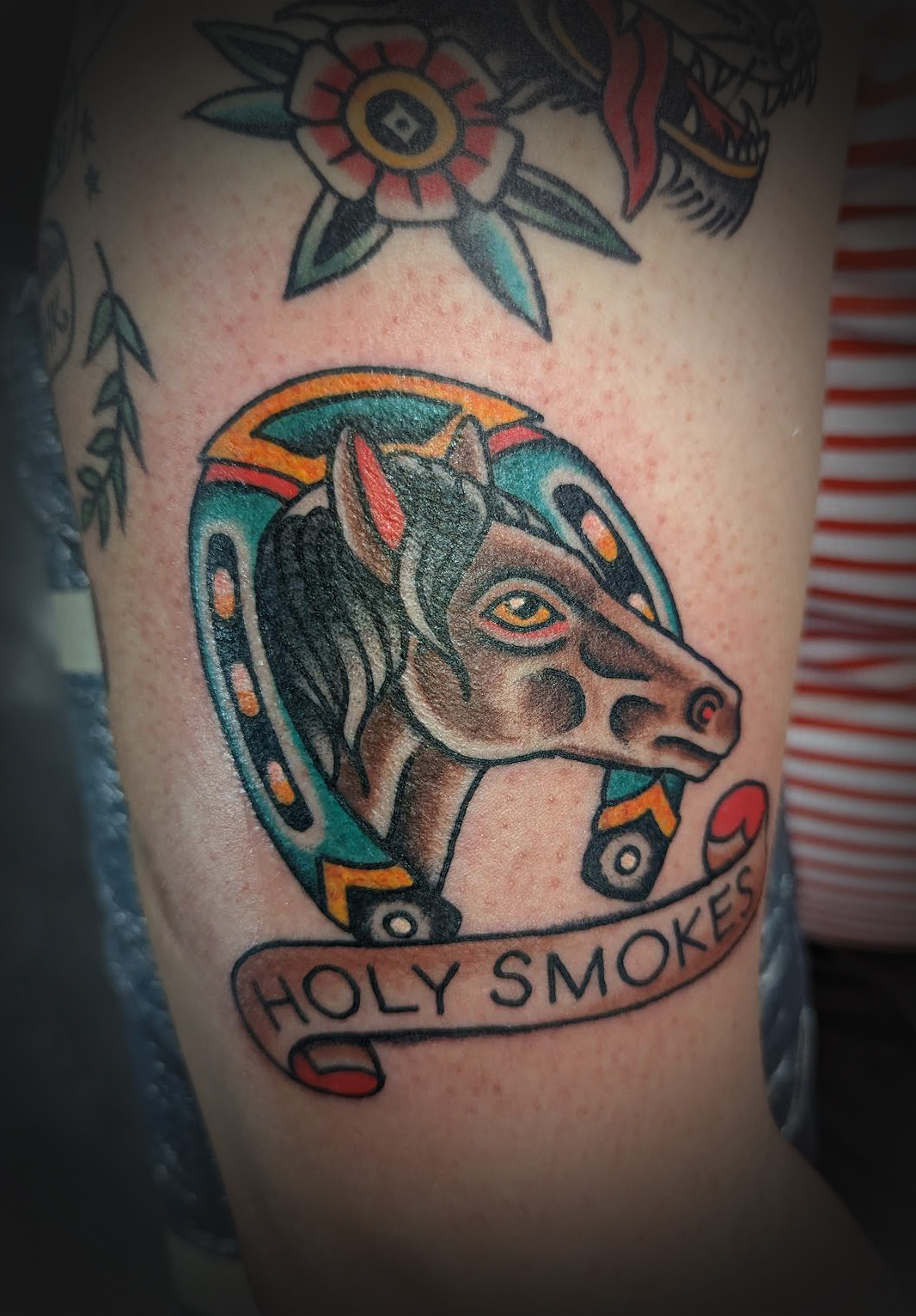 A tattoo of a horse with the words Holy Smokes beneath.